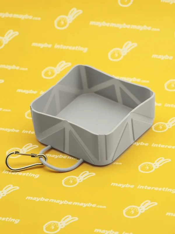 Gray collapsible silicone dog bowl expanded on yellow printed background