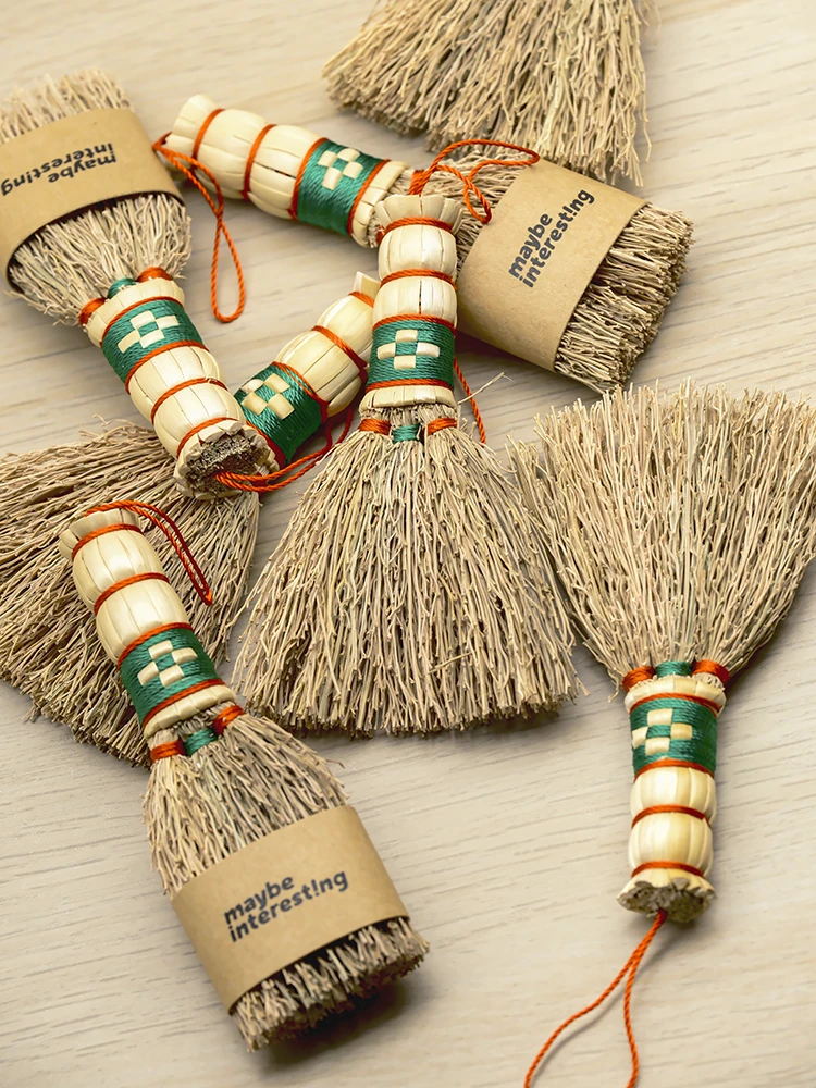 Multiple tiny sorghum broom charms wrapped in craft paper on wooden surface