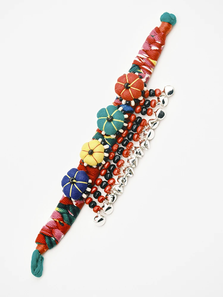 Crimson tie dye fabric bracelet laid flat with pumpkin charms and ring bells